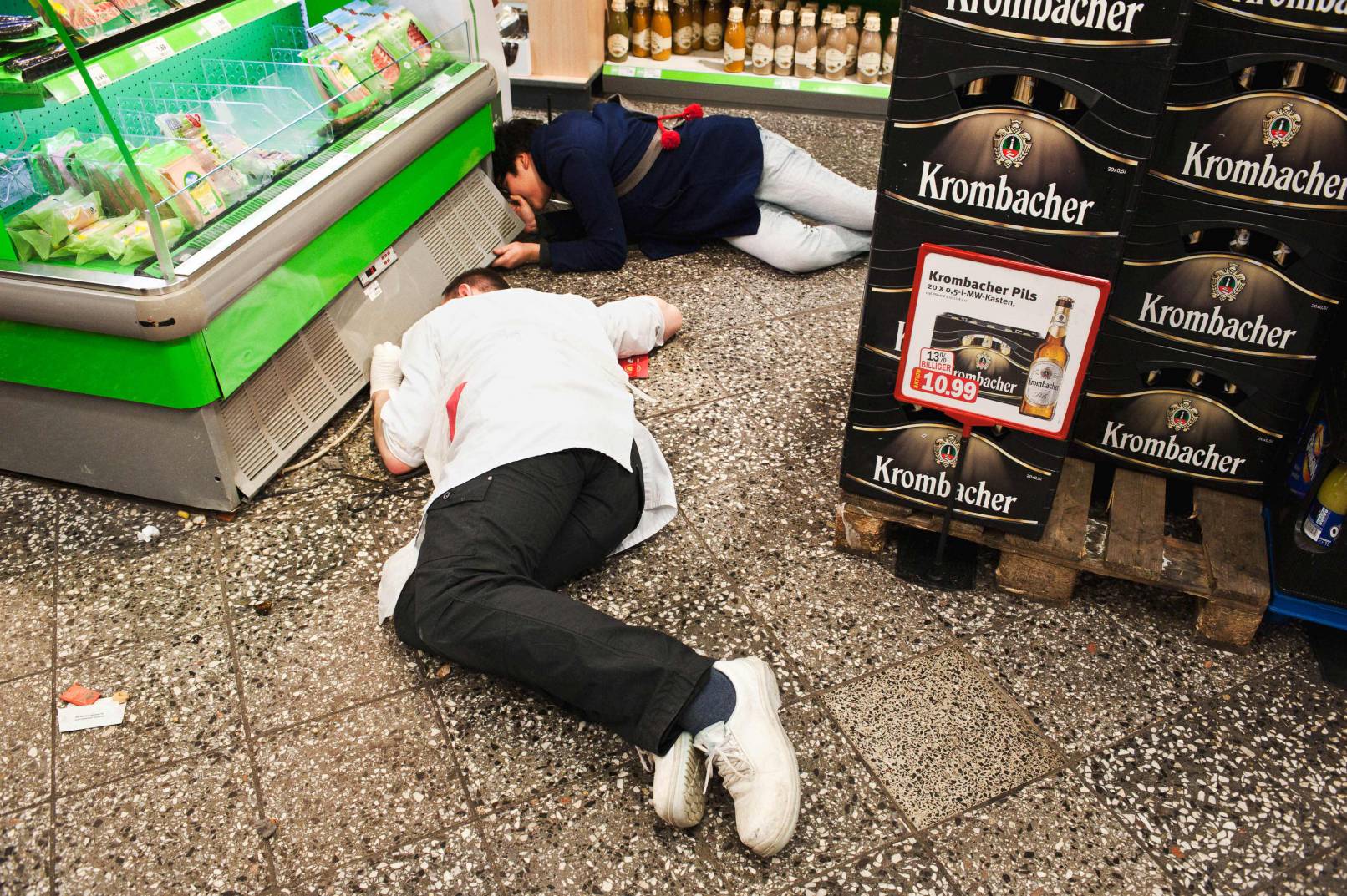 Two person looking for a missing mobile under a shelf in a supermarket, Berlin